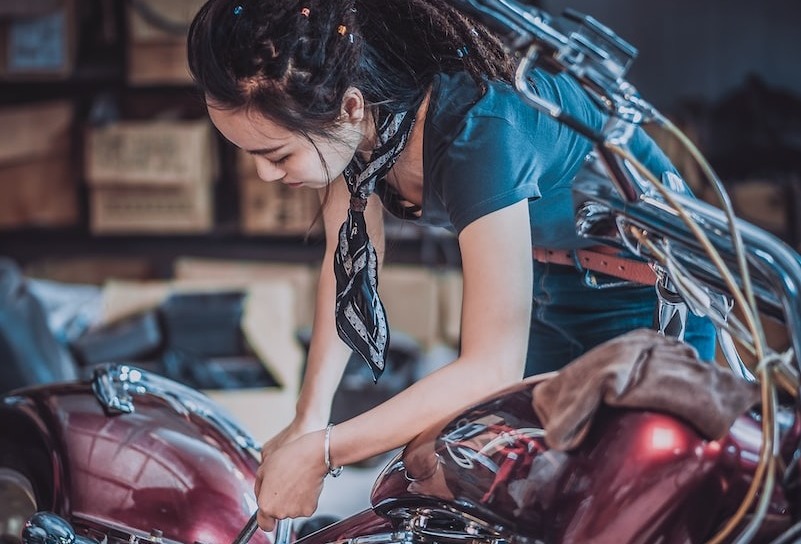 photo of woman repairing motorcycle